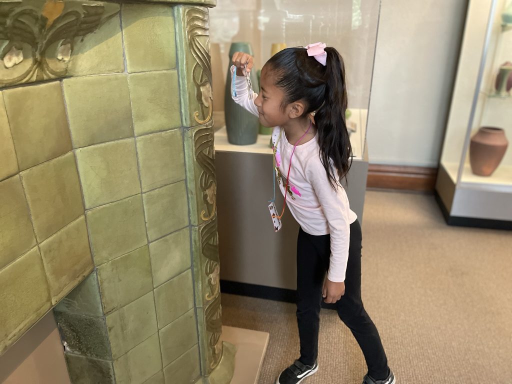 A child looking closely at a Van Briggle Ceramic fireplace in the "Paris to Plains: Van Briggle Pottery Exhibit."