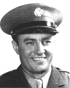 A black and white photo or a man, Floyd K. Lindstrom in a military uniform. Lindstrom an American World War II hero. This photo was taken in 1942 when Lindstrom was a PFC (Private First Class)
