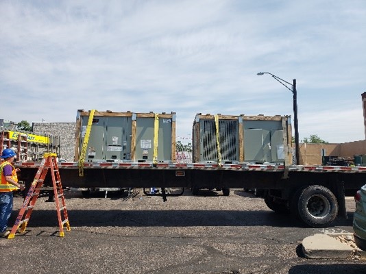 Two HVAC united are strapped onto a flatbed trailer.
