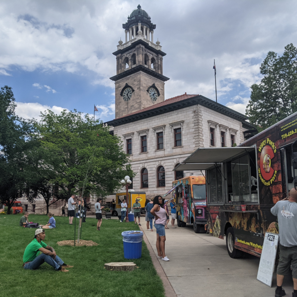 A group of visitors at the Food Truck Tuesdays in 2021 in Alamo Square Park. The CSPM 1903 El Paso County Courthouse is in the background.