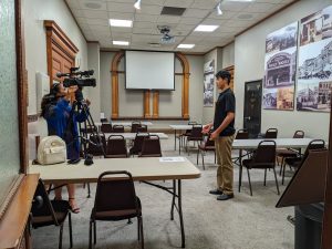 A reporter with a video camera interviews a young man.
