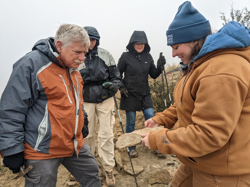 Dr. Maccracken showing Sam Eppley, Christine Eppley, and Barb Winter a fern plant fossil.