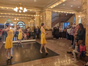 Three dancers from A Time to Dance doing ballet in the lobby of the CSPM.