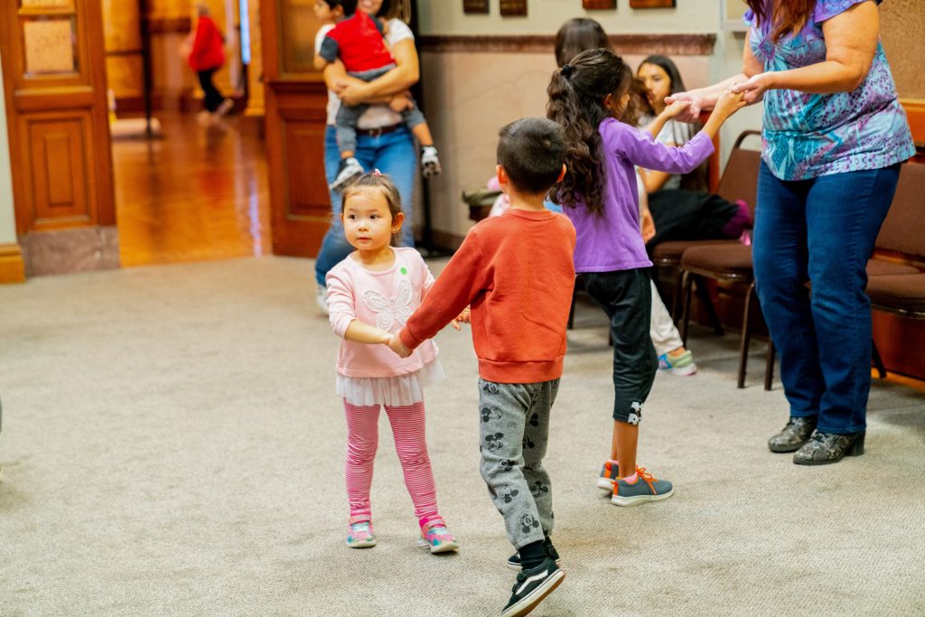Two kids holding hands and dancing in the Family Movement Class.