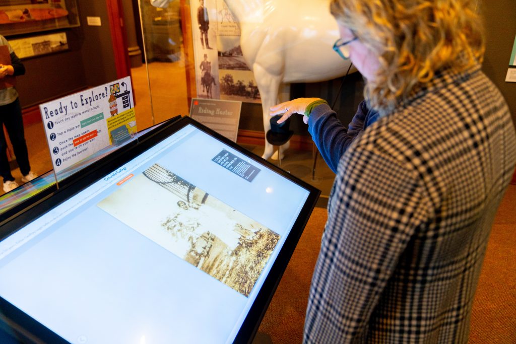 During the Day of Dance, the CSPM unveiled a new Story of Us theme E= Esther Geoffrey. Attendees are looking at the digital exhibit.