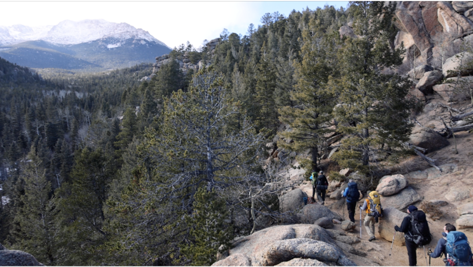 Climbers hiking up to AdAmAn Rest Rock on a single trail. They are heading to s stop to rest before Barr Camp. This photo was taken in 2021,