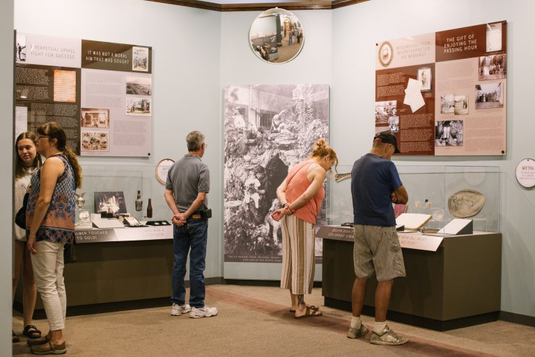 Visitors looking at display cases in "Evidence" exhibit, 2019.
