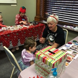 Photo: Sue Bradt Laabs, former CSPM Board member, sitting with a child at the Festival of Lights face painting station.