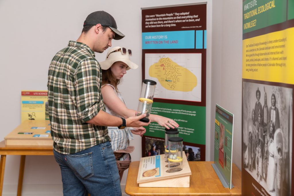 Two adults looking at the hands-on exhibit "Ute Knowledge: Colorado's Original Science, Technology, Engineering, and Math" exhibit in the CSPM Annex.