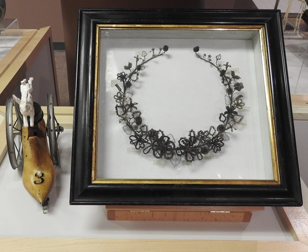 Museum case; abstract rabbit sculpture (left), shadowbox floral crown (right).