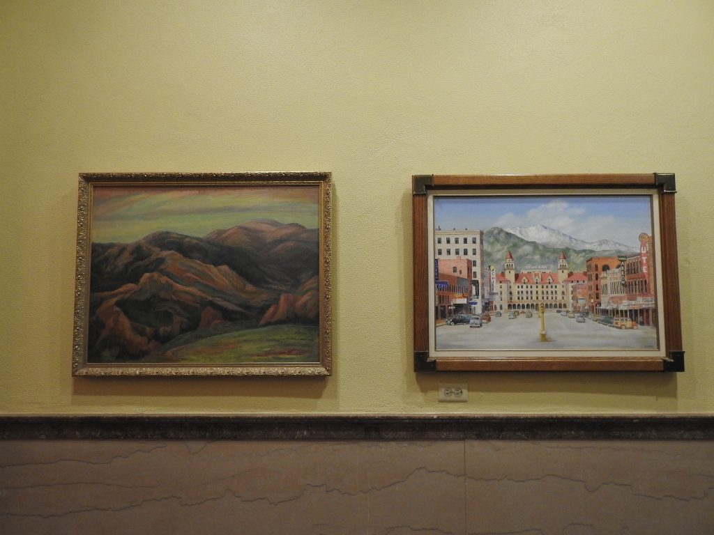 Left, landscape painting of mountains; Right, painting of the Antlers hotel.