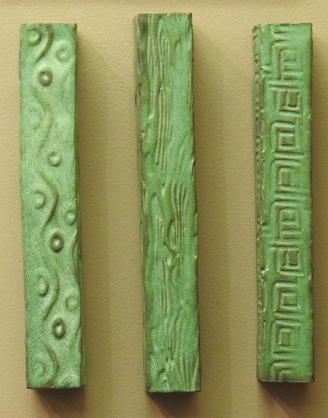 Three dimensional, carved pieces, all painted with a worn green, featuring organic, abstract impressions.