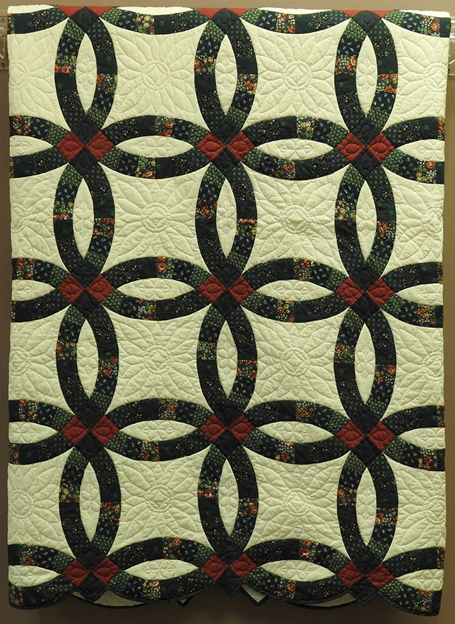 Quilted blanket, designed with interlocking, linking circles. White with earth tone design.