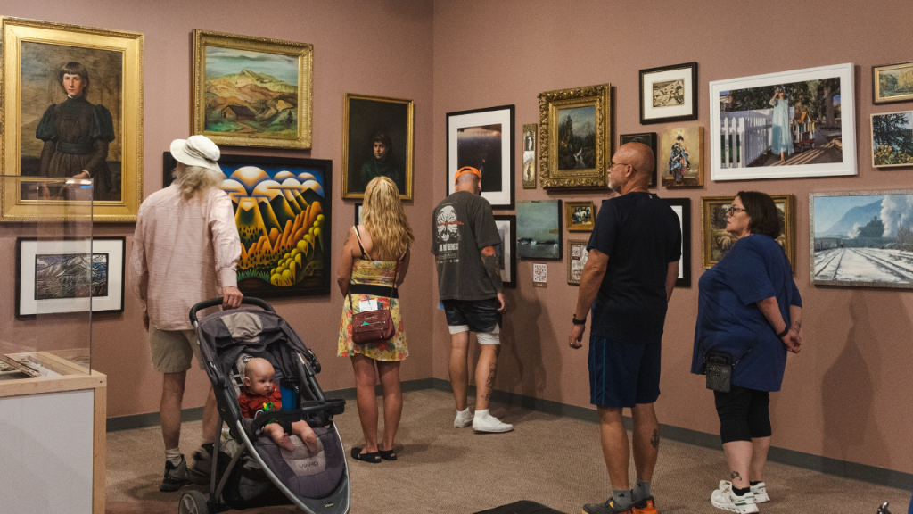 Visitors exploring "50% of the Story: Women Expressing Creativity" Exhibit. This exhibit features a variety of artworks by women artists of the Pikes Peak region. They are hung in a gallery style.