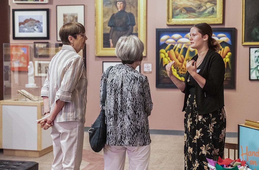 CSPM Intern Violet speaking with attendees in the 50% of the Story exhibit.