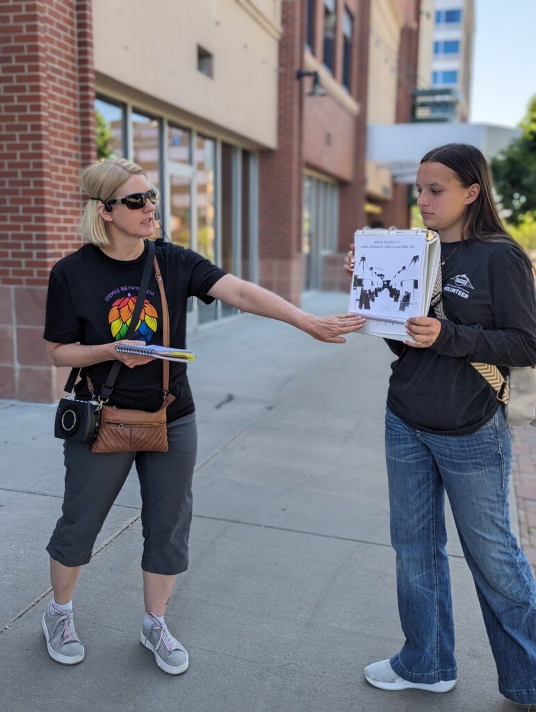 Museum Volunteer showing images to guests while outside on a walking tour.