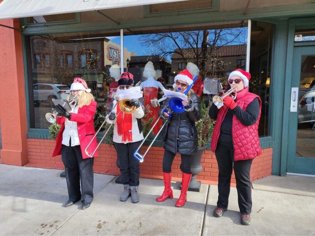 Four brass musicians playing music outside.
