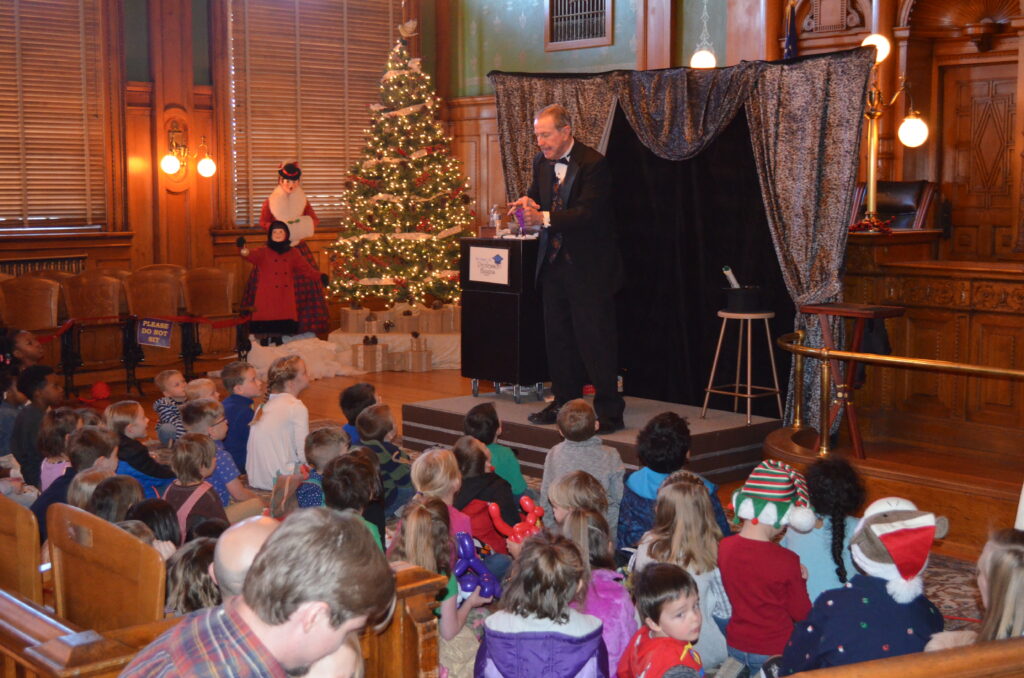 A large group of children enjoying a magic show.