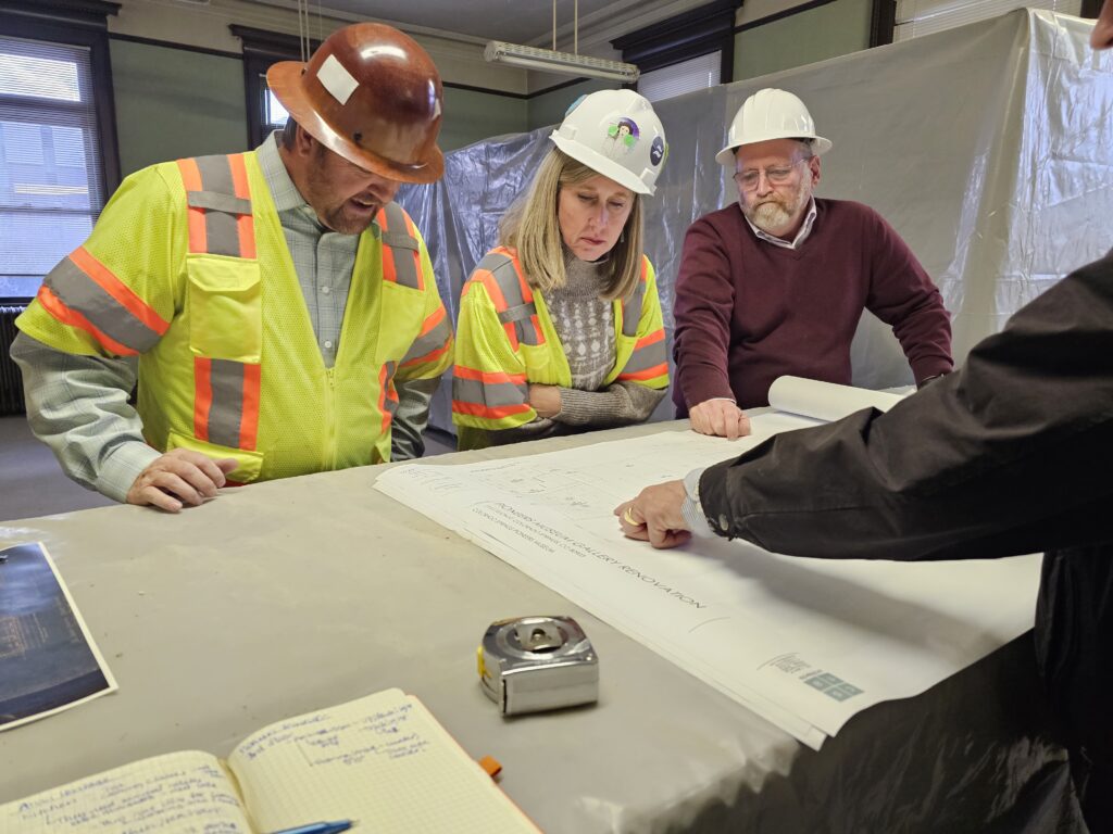CSPM employees and architects gather around a drawing table
